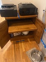 Wooden cabinet base with two doors open showing a pull-out shelf. Items on and inside the cabinet base are not included.