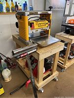 Planer mounted on wooden cart with roller stand in foreground