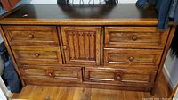 Front view of wooden dresser showing all drawers and central decorative panel
