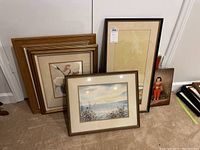 Group of framed artworks and decorative items including framed watercolor, prints, string art set and wall plaque.