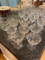 View of dessert glasses in the front with etched floral pattern, and other glasses behind