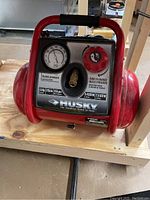 Front view showing the Husky air compressor label with specifications including 1.5HP, 3 gallons, 155 PSI max, outlet pressure gauge and pressure adjustment knob.