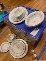Photo showing multiple serving pieces including gravy boat, oval serving bowls, and platters with Camille floral pattern and silver trim placed on a plastic storage bin.