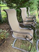 Group of four chairs outdoors, metal frames with curved armrests and sling seats