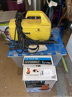 Karcher yellow pressure washer, black spray gun and power cord, Everbilt utility pump box shown beneath