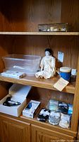 Wooden shelf with China doll, plastic box, peel off mask, musical drum and display box with thimbles