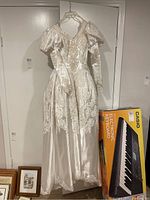 Full view of 1993 ivory wedding dress hanging on door, showing long puffed sleeves and skirt