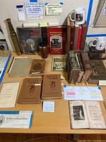 Full lot view on table showing books, mugs, map, receipt and spyglass