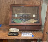 Lot overview showing brass button balance scale in wooden glass case with handheld scale and accessories