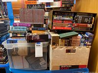 Photo of multiple boxes and shelves filled with audio book cassettes and CDs, various titles visible including David Baldacci and Maeve Binchy