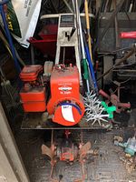 Front view of red Montgomery Ward Power Reverse tiller with Briggs & Stratton engine and tines