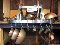 Overview of chrome pot rack loaded with copper cookware