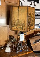 Photo of the table lamp showing metal base and London-themed paper shade with illustration of Nelson's Column and nearby architecture.