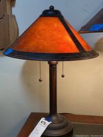 Front view of the mica table lamp illuminated showing the amber color glow of the shade.