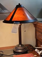 Full side view of mica table lamp showing conical mica shade with dark metal trim, vertical ridged metal stem, and circular base.