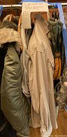 Various military cold weather clothing items hanging on a rack including parka, pants, and shirts.