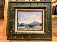 Front view of the framed painting showing the textured green frame with linen liner and the desert landscape oil painting inside.