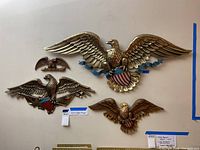 Set of three eagle plaques displayed on wall, largest features blue ribbon and shield