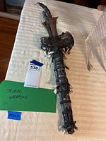 Full view of the tribal double-edged weapon showing the blade and wrapped leather handle with bone accents.