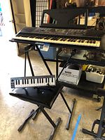 Yamaha PSR keyboard on X-style keyboard stand with M-Audio Keystation 32 Mini keyboard and folding instrumentalist seat below it