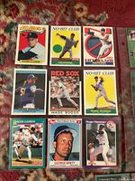 Array of baseball cards featuring players including Roger Clemens, Nolan Ryan, Randy Johnson, Wade Boggs, and George Brett arranged on fabric surface.