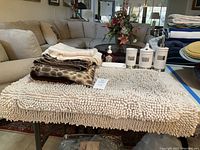 Shower curtains (animal print and floral), cream colored textured bath mat set, and vanity set including dispensers and holders.