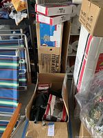 Open box showing green extension cords and boxes of holiday lights/Christmas tree components.