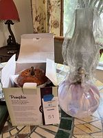 Photo of iridescent glass oil lamp next to Scentsy pumpkin wax warmer box on tiled table.