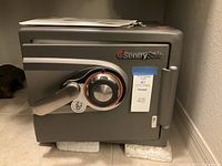 Front view of gray SentrySafe safe showing brand logo, combination dial, handle, and key lock.