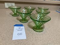 Six green footed dessert cups with spiral swirl pattern arranged on a kitchen counter.