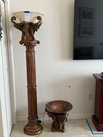 Full view of wood carved elephant pillar lamp and matching decorative bowl on elephant stand shown against a white wall near a television.