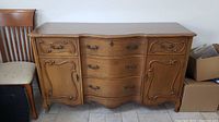 Front view of hardwood bureau or buffet showing five drawers in center and two cupboard doors on sides with decorative paneling and metal handles