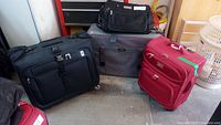 Overall view of the 3 bags: black carry-on, gray large suitcase, red medium suitcase
