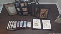 Photo showing 20 assorted picture frames arranged on a floor, showcasing variety in size, color and some with artwork.