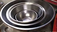 Five stainless steel mixing bowls nested inside each other showing size variation and polished finish.