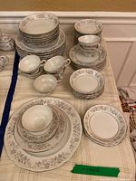 Full view of stacked plates, bowls, saucers and tea cups laid out on table