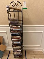 Black metal wire rack filled with assorted DVDs and CDs stacked vertically