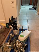 Overall view of the crock filled with kitchen utensils on a tray including flatware and kitchen tools