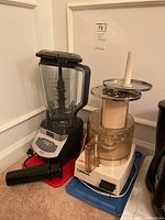 NINJA blender and Cuisinart food processor shown side by side on floor with bases and pitchers/containers visible