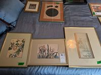 Six assorted Asian theme wall art pieces laid out on a gray fabric surface showing different sizes and styles of prints and frames.