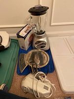 Oster blender, Hamilton Beach hand beaters, and Progressive kitchen scale in original box arranged for photo