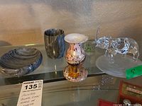 Full view of the lot including painted glass vase marked Gozo Glass, clear glass elephant figurine, gray soap dish, metallic cup, and small glass cup.