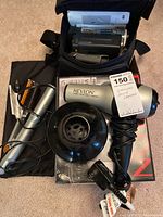 Lot items on floor showing Samsung camcorder in carrying case, Revlon hair dryer with diffuser and comb attachment, and InStyle black hair straightener with pouch.