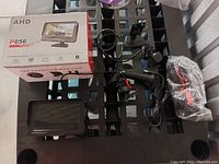 Photo showing the AHD P056 car rearview monitor, mount, cables, connectors, and the product box