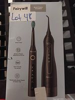 Photo shows Fairywill branded oral care combo set box with image of black electric toothbrush and water flosser, with handwritten label Lot 48.