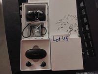Photo showing two boxed sets of hearing aid or earbud style devices along with accessories in packaging for Lot 45.