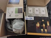Photo of flexible LED desk lamp in box with control instructions, in-wall smart switch modules, and LED tea light pack.