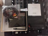 Neewer T7 LCD Field Monitor and accessories including antenna, cables, stylus, and manual in box.