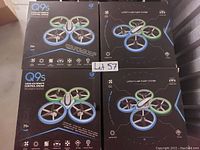 Photo showing four boxes of Q9S remote control drones with light-up feature, model Q9S, showing drone image on the packaging with blue and green LED rings around rotors.