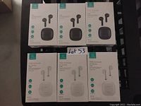 Six sealed boxes of TWS wireless earbuds IA Series, three black, three white, stacked on a shelf with lot tag visible.